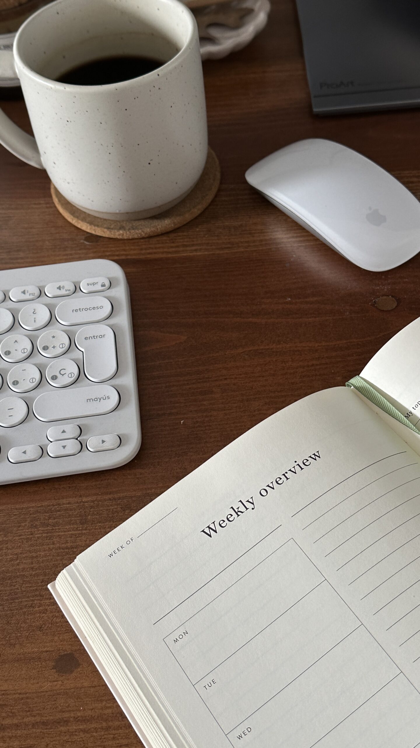 CPG social media strategist from Seen & Shared Marketing explains social media workflows while sitting at her brown desk with a cup of coffee, a white planner, and white computer keyboard